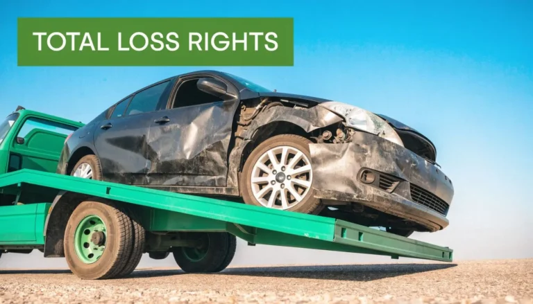 A severely damaged car loaded on a tow truck bed representing a total loss vehicle accident.