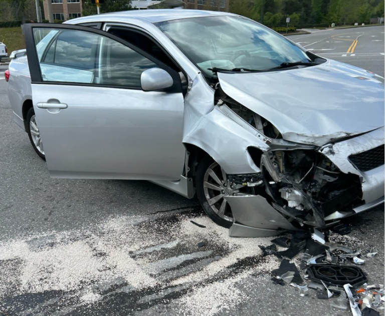 Severe front-end damage on a car following a collision at a street intersection